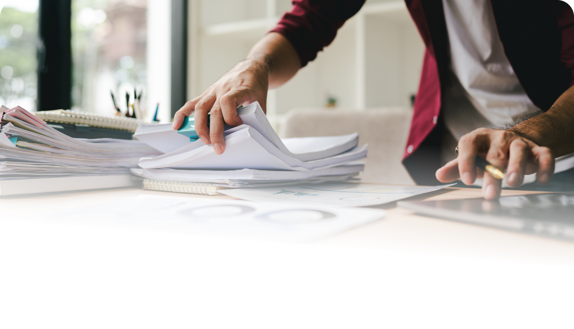 Man at desk looking through stacks of papers