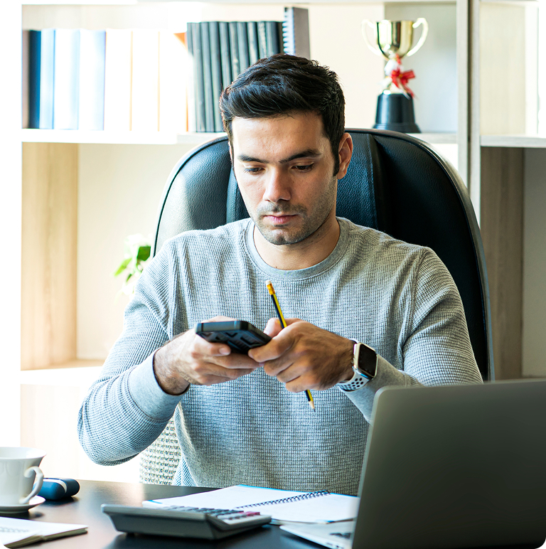 Man sitting at office desk looking at mobile phone