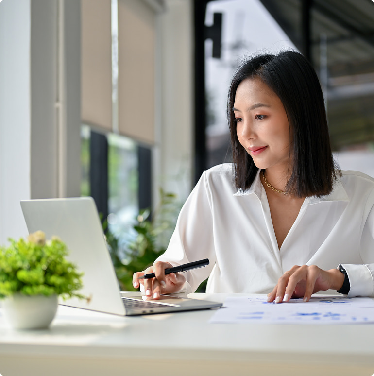 Woman at laptop computer holding a pen